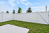 Charming backyard with lush green grass, enclosed by a crisp white privacy fence, perfect for relaxation and outdoor activities.