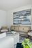 Elegant living room corner with modern decor, featuring a plush armchair, abstract artwork, and a chic wood console. The room exudes comfort and style, ideal for sophisticated living.
