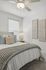Bright and cozy bedroom featuring a stylish bed with textured pillows, soft knit blanket, modern lamp, and elegant artwork on the wall.