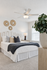 Inviting bedroom with elegant decor, featuring a cozy bed adorned with decorative pillows, stylish wall art, and a lush plant by the window.