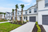 Charming townhome exterior featuring modern architecture, lush landscaping, and elegant palm trees in a vibrant residential community.