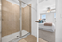 Modern bathroom with sleek glass shower leading to a bright bedroom featuring chic decor and natural light.