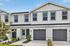 Charming two-story townhouse with modern gray accents, featuring private garages and manicured landscaping, perfect for contemporary living.
