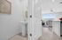 Bright, contemporary bathroom with elegant pedestal sink and modern decor, leading into a sunlit living room with cozy seating and large windows.