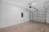 Spacious modern garage with sleek white walls and a sturdy metal door, ideal for secure parking and storage.