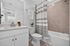 Modern bathroom with sleek white cabinetry, elegant shower curtain, and stylish tile accents.