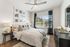 Inviting bedroom with modern decor featuring large window, abstract art, and elegant neutral tones.