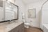 Elegant bathroom with sleek granite countertops, a large mirror, and modern lighting. Features wood-style flooring and inspiring wall art.