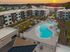 Chic apartment complex with modern architecture featuring a stunning pool area, outdoor seating, and lush landscaping at sunset.
