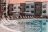 Modern apartment complex showcasing a luxurious swimming pool with stylish lounge chairs and sleek poolside design.