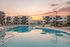 Modern apartment complex with a pristine swimming pool and cozy outdoor lounging area at sunset.