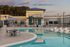 Luxurious outdoor pool area at sunset featuring sleek white lounging chairs, elegant patio seating, and modern architecture.