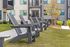 Modern apartment exterior with stylish Adirondack chairs on a lush green lawn, perfect for relaxation and social gatherings.