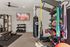 Modern fitness room with state-of-the-art equipment including a weight rack, punching bag, and resistance bands, perfect for a comprehensive workout.
