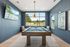 Chic entertainment room with modern pool table, stylish decor, and large windows offering scenic views.