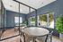 Charming communal space with elegant round wooden tables, stylish chairs, and expansive windows offering serene outdoor views.