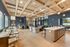 Inviting open-concept communal area featuring modern wood beam ceilings, a sleek kitchen island, and cozy seating with natural light streaming through large windows.
