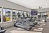Contemporary fitness center with large windows, featuring modern treadmills and stationary bikes, overlooking a vibrant outdoor space.