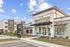 Modern apartment complex exterior with a welcoming club entrance, pristine landscaping, and bright blue skies.