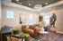 Elegant living room with modern decor, featuring a stylish brown leather couch, chic lighting fixture, and contemporary artwork, creating a cozy atmosphere.