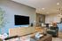 Modern open-plan living room with stylish decor, featuring a sleek TV setup, elegant furniture, and a cozy dining area with contemporary lighting.