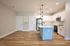 Modern open-concept kitchen with sleek stainless steel appliances, elegant white cabinetry, and stylish pendant lighting on warm hardwood floors.