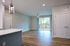 Bright and modern apartment interior highlighting sleek hardwood floors, a spacious open-plan layout, and large sliding glass doors leading to a scenic balcony.