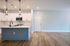 Modern kitchen with elegant pendant lighting, sleek white cabinets, and a spacious island, complemented by a warm wood floor.