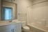 Elegant bathroom featuring a modern vanity with marble countertop, large mirror, and a sleek shower-tub combination.