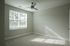 Bright and airy bedroom with modern ceiling fan and large window, perfect for natural light lovers.