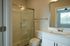 Modern bathroom with sleek glass-enclosed shower, stylish vanity, and large mirror, offering a bright and refreshing space.