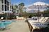 Charming outdoor pool area with elegant lounge chairs and stylish umbrellas, set against modern apartment buildings and lush greenery.