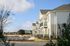 Modern apartment complex featuring charming balconies, surrounded by lush greenery and bright blue skies.