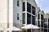 Charming three-story apartment building with spacious screened balconies and stylish exterior, enhanced by inviting outdoor umbrellas.