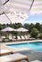 Luxurious outdoor pool area featuring elegant lounge chairs and stylish striped umbrellas, perfect for relaxation and sunshine.