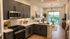 Contemporary open-concept kitchen and living room with elegant decor, featuring sleek cabinetry, modern appliances, and a bright balcony view.