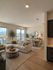 Elegant open-plan living and dining area with modern furnishings, large windows showcasing city views, and natural wood flooring.