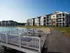 Luxury waterfront apartments with modern balconies and serene lakeside views, featuring a private dock with comfortable seating.