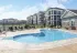 Sparkling pool with lounge chairs, with a backdrop of beautiful apartments.