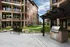 Charming apartment exterior with manicured green courtyards, modern stone facade, and outdoor BBQ area, perfect for leisure and gatherings.