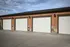 Modern row of three garage doors with elegant stone accents and warm brown tones, offering secure parking solutions.