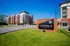 Bright and modern Uptown Terrace apartment complex with red brick facade, ample balconies, and lush green surroundings.