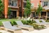 Upscale apartment complex with lush greenery, modern balconies, and luxurious outdoor lounge chairs for relaxation.