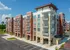 Modern multi-story apartment building with spacious balconies, vibrant brick facade, and ample parking set against a clear blue sky.