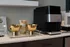 Chic coffee station with a sleek black coffee machine and elegant gold bowls on a modern countertop, offering a touch of luxury.