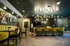 Modern lounge area featuring stylish yellow seating, sleek bar stools, artistic wall decor, and ambient lighting creating a warm, inviting atmosphere.