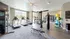 Modern fitness center with state-of-the-art equipment, including treadmills, exercise bikes, and a boxing bag, set in a bright and spacious room with large windows.