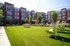 Modern apartment complex with vibrant green courtyard, relaxing lounge chairs, and charming outdoor string lights.