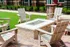 Charming outdoor patio with stylish Adirondack chairs surrounding a modern brick fire pit on a vibrant green lawn background.