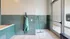 Chic utility room with stylish teal subway tiles, featuring a modern glass door entrance and convenient cleaning tools.
